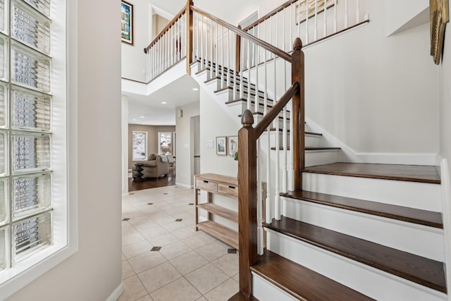 stairway featuring tile patterned flooring, baseboards, a high ceiling, and recessed lighting