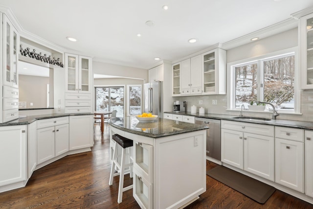 kitchen with tasteful backsplash, white cabinets, appliances with stainless steel finishes, dark wood-type flooring, and a sink