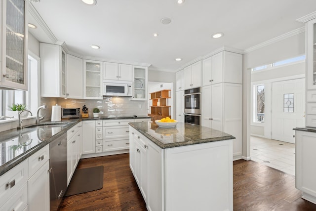 kitchen featuring crown molding, backsplash, appliances with stainless steel finishes, white cabinets, and a sink