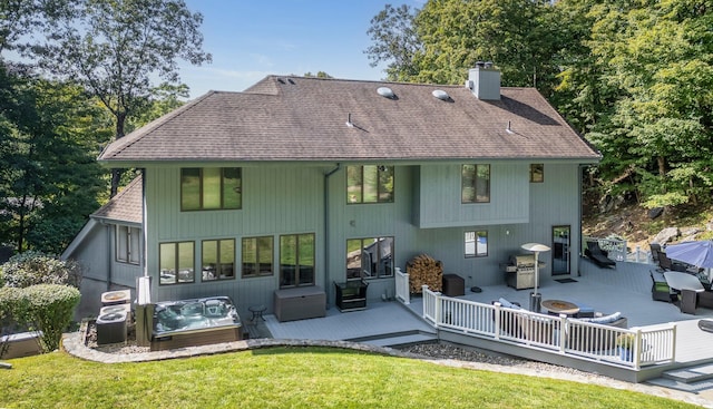 rear view of house with a yard, a chimney, a hot tub, central AC, and a wooden deck