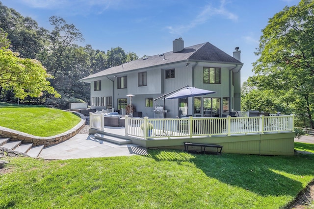 back of property with a deck, a shingled roof, an outdoor living space, a lawn, and a chimney