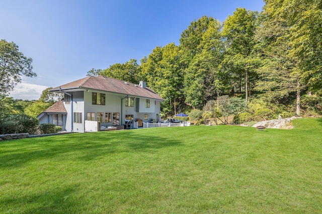 back of property with a yard, a chimney, and a patio