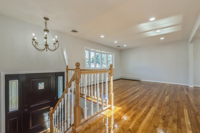 foyer entrance featuring wood-type flooring and an inviting chandelier