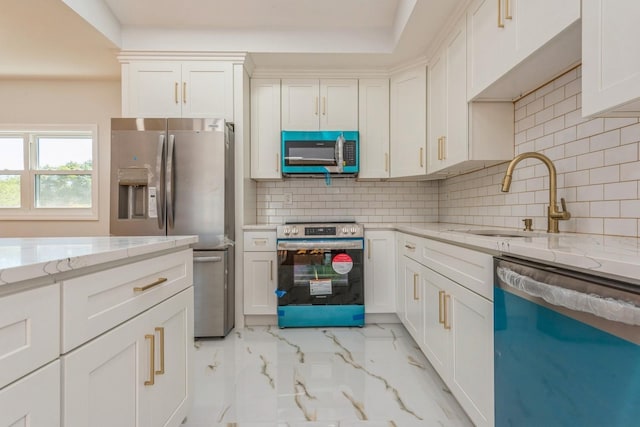 kitchen featuring appliances with stainless steel finishes, backsplash, light stone counters, sink, and white cabinets