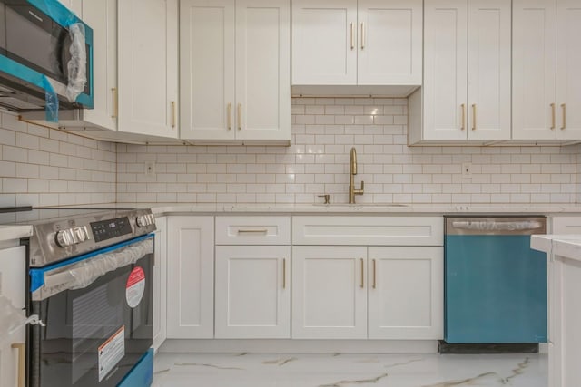 kitchen with backsplash, white cabinets, sink, and stainless steel appliances