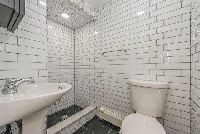 bathroom featuring sink, tile patterned flooring, a shower, toilet, and tile walls