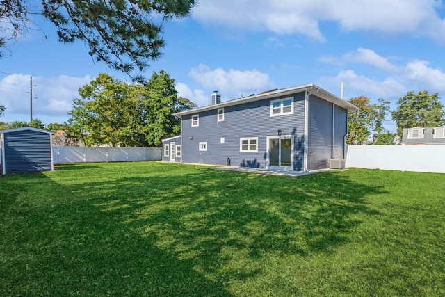 rear view of house with a lawn and a storage unit