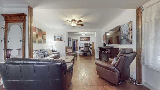 living room with wood-type flooring, ceiling fan, ornamental molding, and a premium fireplace