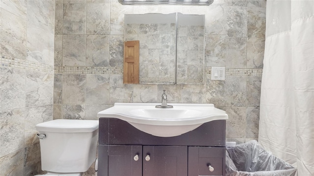 bathroom with vanity, toilet, and tile walls