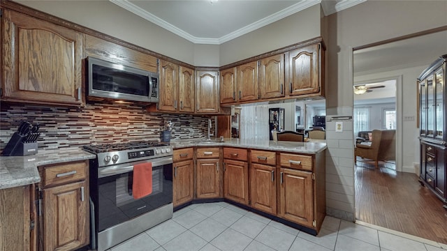 kitchen featuring light stone countertops, ornamental molding, stainless steel appliances, ceiling fan, and light tile patterned floors