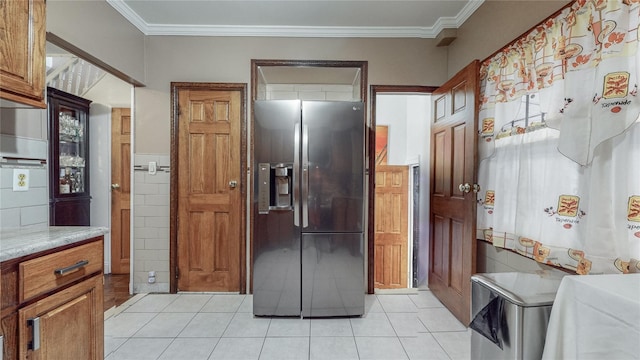 kitchen featuring stainless steel fridge, crown molding, light tile patterned floors, and tile walls