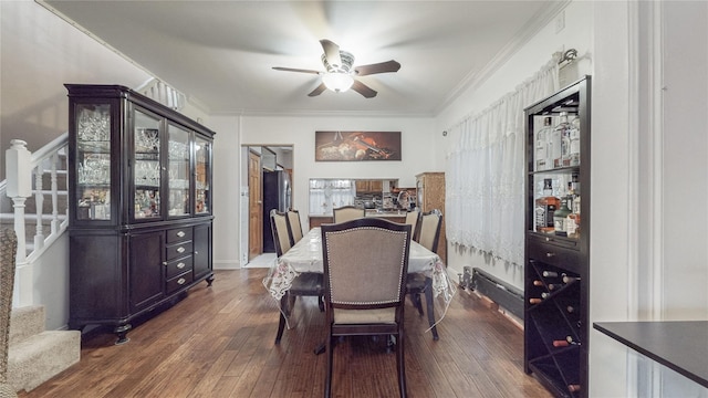 dining area with ceiling fan, crown molding, and dark wood-type flooring