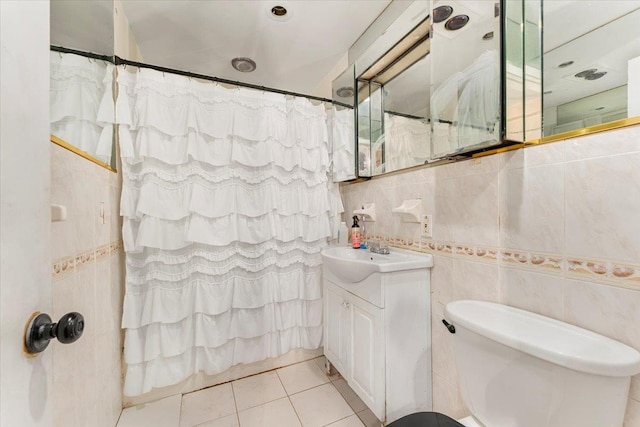 bathroom with tile patterned floors, vanity, toilet, and tile walls