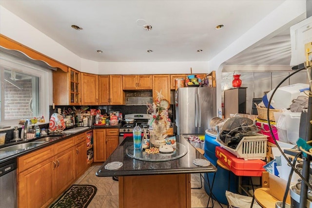 kitchen featuring decorative backsplash, dark stone counters, stainless steel appliances, sink, and a center island