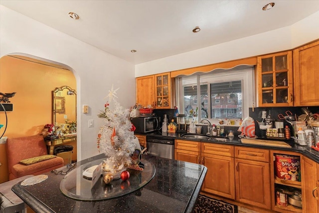 kitchen with stainless steel dishwasher, dark stone counters, and sink