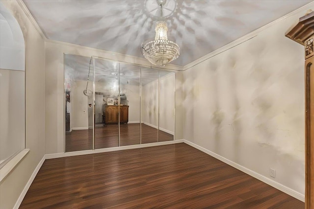 unfurnished dining area featuring dark hardwood / wood-style flooring, crown molding, and a chandelier