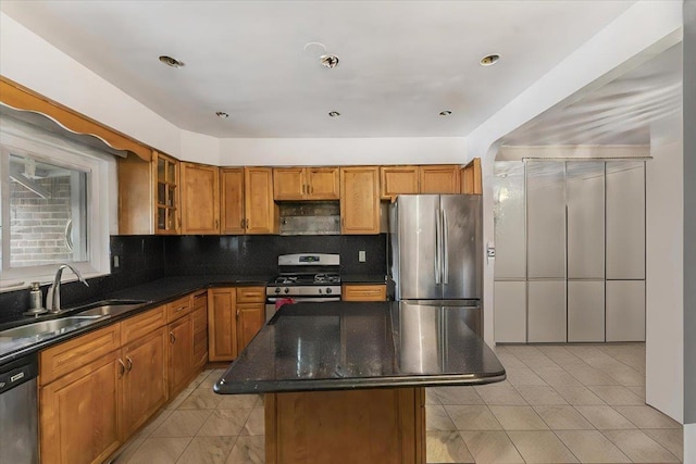 kitchen with a center island, dark stone counters, sink, light tile patterned floors, and stainless steel appliances