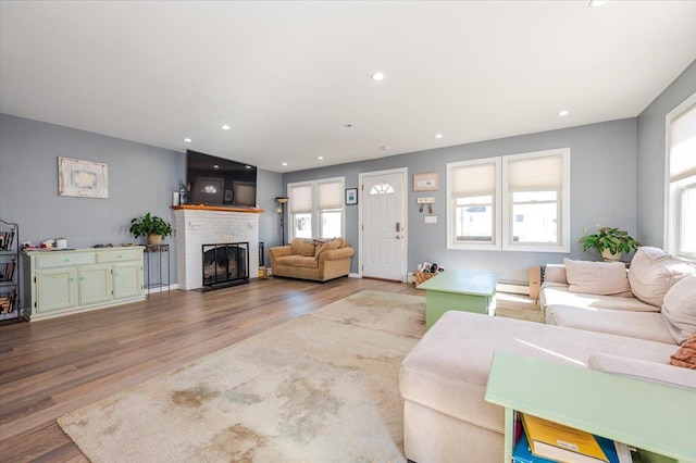 living room with hardwood / wood-style floors, a baseboard heating unit, and a brick fireplace