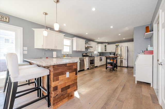 kitchen with kitchen peninsula, white cabinetry, hanging light fixtures, and appliances with stainless steel finishes