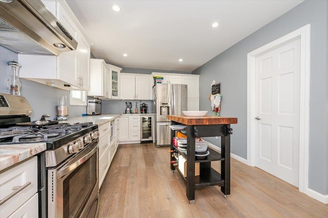 kitchen with ventilation hood, wine cooler, white cabinets, and appliances with stainless steel finishes