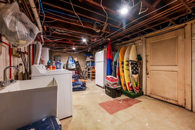 basement featuring electric panel, washer and clothes dryer, white fridge, and sink