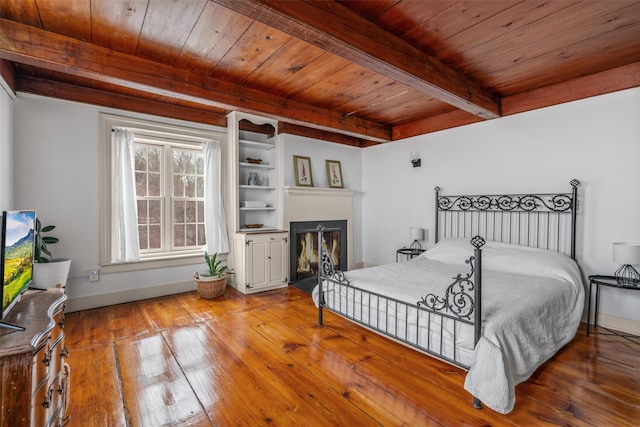 bedroom with beam ceiling, hardwood / wood-style flooring, and wooden ceiling