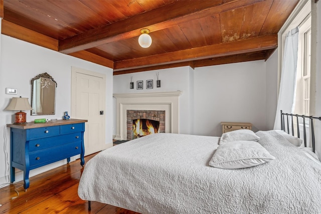 bedroom featuring a brick fireplace, wood ceiling, dark hardwood / wood-style floors, and beamed ceiling