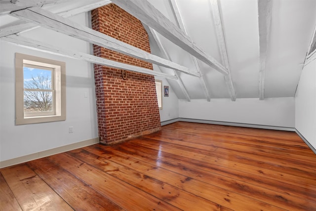 additional living space with lofted ceiling with beams, brick wall, and hardwood / wood-style flooring