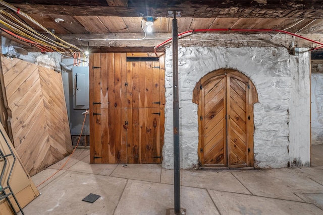 basement with wood ceiling, wood walls, and electric panel