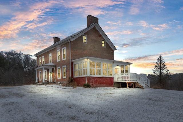 property exterior at dusk with a deck and a sunroom