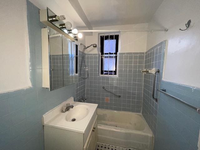 bathroom with tile walls, tiled shower / bath combo, and vanity