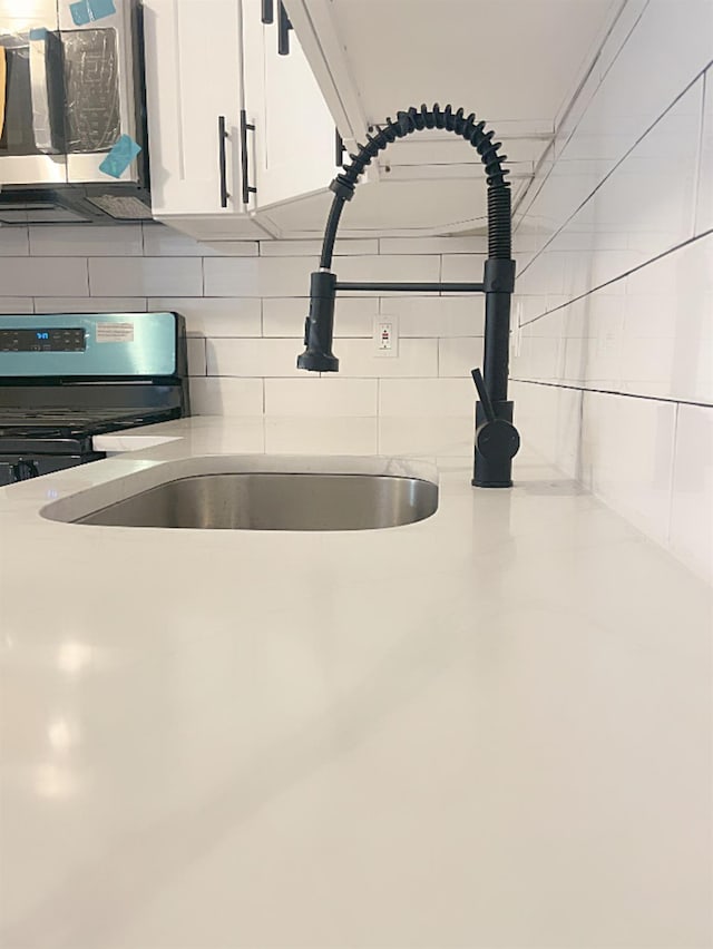 details with white cabinets, decorative backsplash, and stove