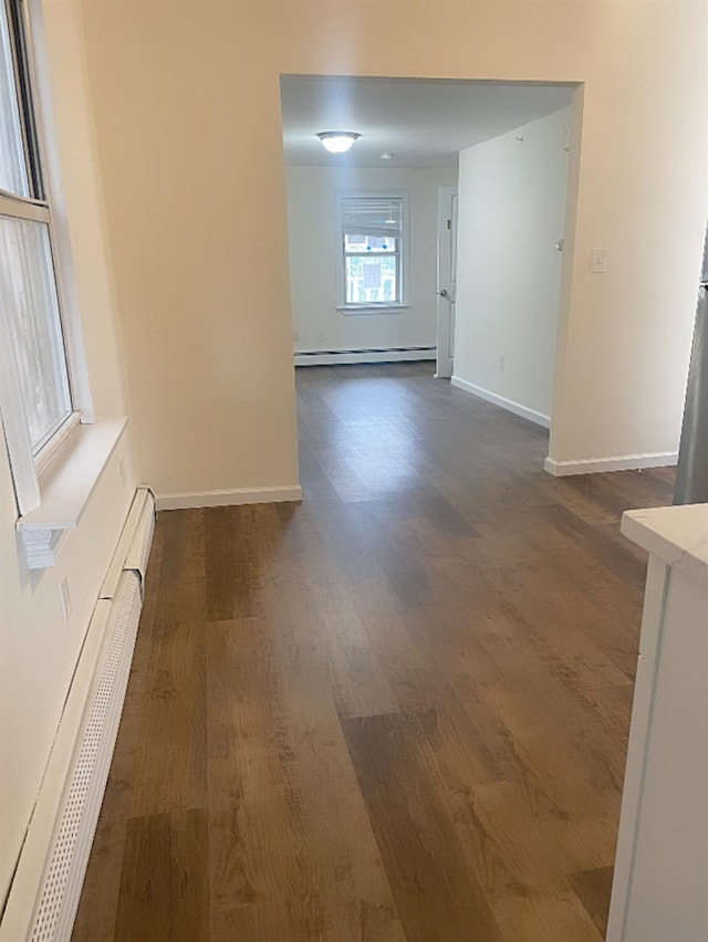 unfurnished room with dark hardwood / wood-style flooring and baseboard heating