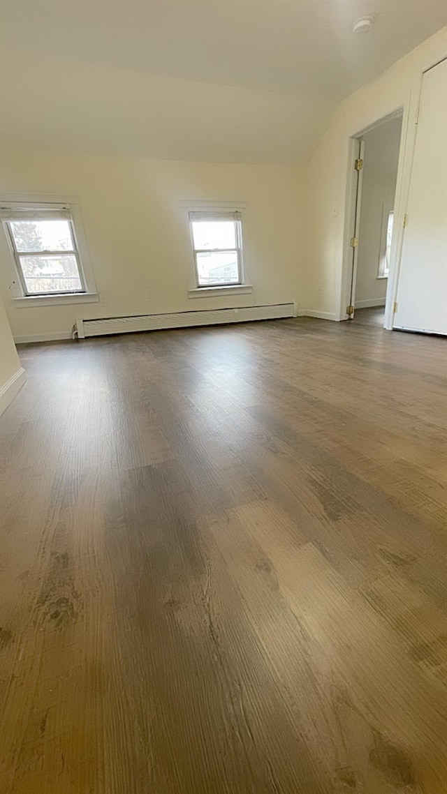 spare room with wood-type flooring, a baseboard radiator, and lofted ceiling