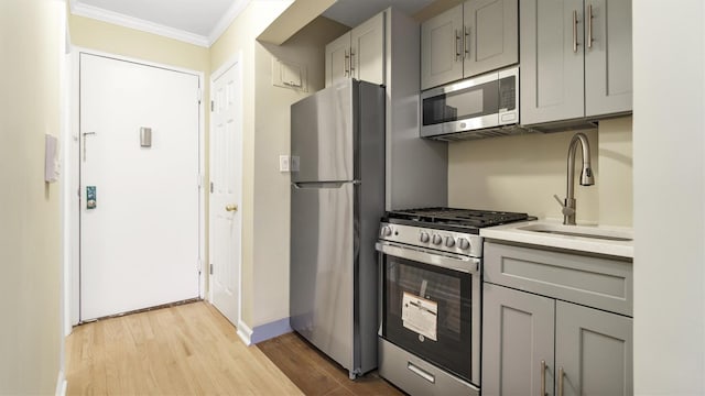 kitchen with ornamental molding, stainless steel appliances, gray cabinetry, and sink