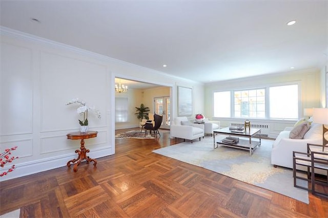 living room featuring dark parquet floors, crown molding, and an inviting chandelier