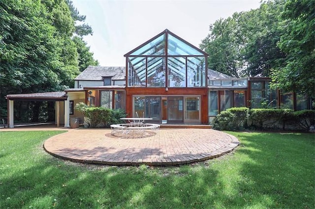 back of property featuring a patio, a lawn, and a sunroom