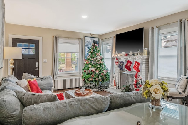 living room featuring radiator heating unit and a brick fireplace