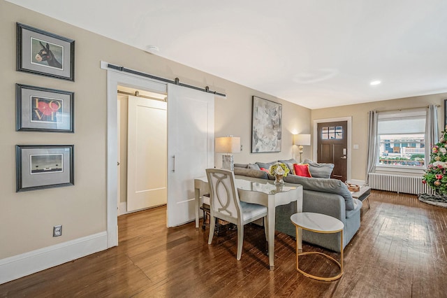 living room with radiator heating unit, a barn door, and hardwood / wood-style flooring