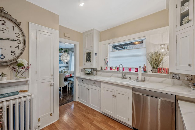 kitchen with light wood-type flooring, radiator, sink, dishwasher, and white cabinetry