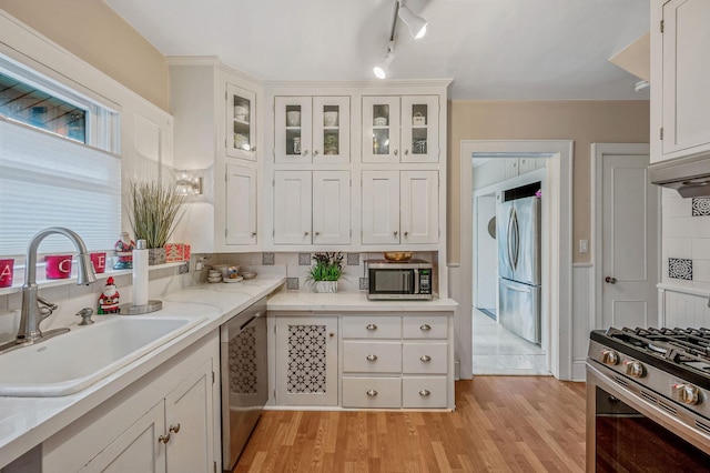 kitchen with appliances with stainless steel finishes, light hardwood / wood-style flooring, white cabinetry, and sink