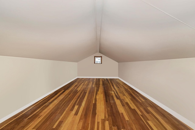 additional living space with vaulted ceiling and dark wood-type flooring