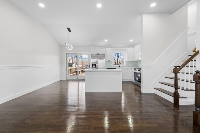 kitchen with pendant lighting, a center island, backsplash, white cabinets, and stainless steel appliances