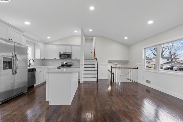 kitchen with a center island, white cabinets, lofted ceiling, and appliances with stainless steel finishes