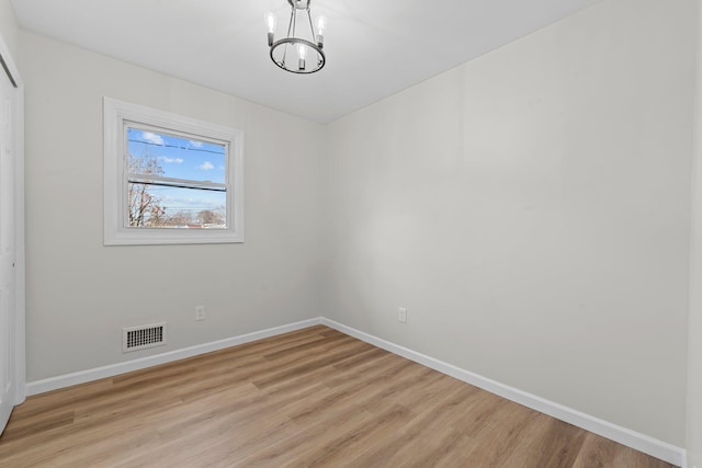 unfurnished room with light hardwood / wood-style flooring and an inviting chandelier