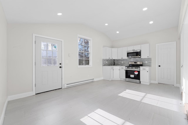 kitchen featuring white cabinets, vaulted ceiling, tasteful backsplash, stainless steel appliances, and a baseboard radiator