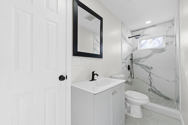 bathroom featuring tile patterned floors, vanity, toilet, and a tile shower