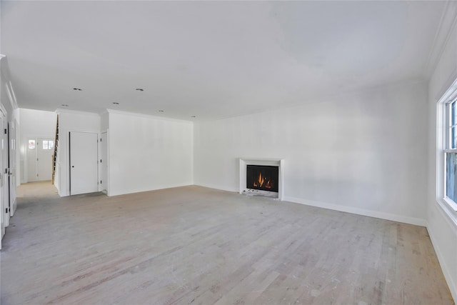 unfurnished living room featuring plenty of natural light, ornamental molding, and light hardwood / wood-style flooring