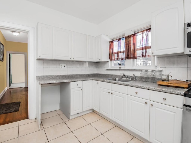 kitchen featuring white cabinets, decorative backsplash, light tile patterned floors, and sink