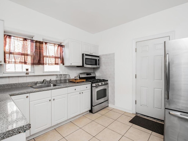 kitchen with white cabinets, sink, light tile patterned floors, tasteful backsplash, and stainless steel appliances